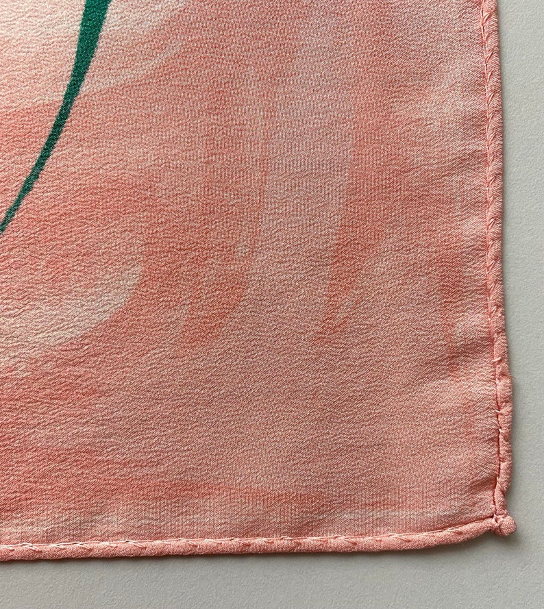 Puede incluir: Primer plano de una tela rosa con un dise&ntilde;o verde. La tela tiene una superficie texturizada y est&aacute; bordeada con una costura cosida.