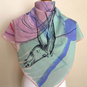 Puede incluir: Un pa&ntilde;uelo de seda cuadrado con un dise&ntilde;o abstracto en rosa, verde y azul. El pa&ntilde;uelo presenta un dibujo en blanco y negro de un p&aacute;jaro en vuelo.