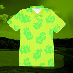 Puede incluir: Una camisa polo de color amarillo brillante con estampado floral tropical. Las flores son de un tono verde m&aacute;s claro.