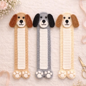 Könnte beinhalten: Drei handgefertigte Lesezeichen in Hundeform aus Häkelarbeit in Beige, Grau und Creme. Jedes Lesezeichen zeigt einen Hundekopf mit Schlappohren und ein Pfotenabdruck-Design. Auf weißem Hintergrund.