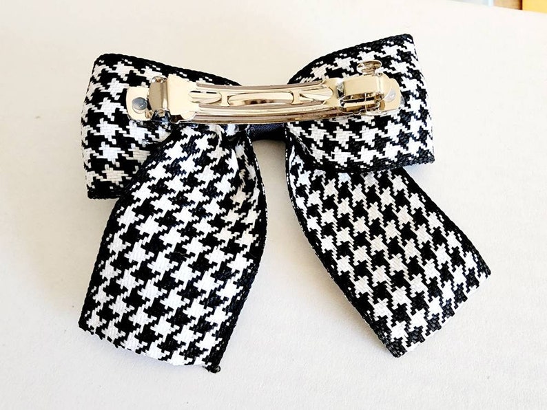 May include: Black and white houndstooth bow hair clip with a silver metal alligator clip.