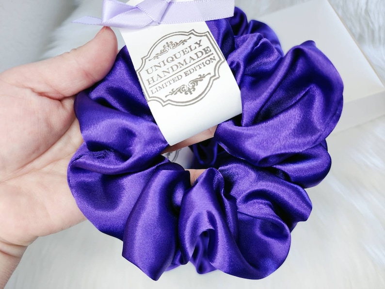 May include: A purple satin scrunchie with a tag that reads "Uniquely Handmade Limited Edition".