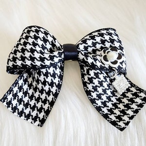 May include: A black and white houndstooth bow with a black satin center and a white pearl flower accent.