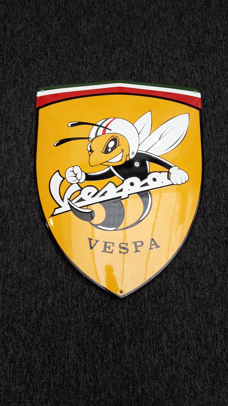 K&ouml;nnte beinhalten: Ein gelbes und schwarzes Vespa-Logo mit einer Cartoon-Biene, die einen Helm tr&auml;gt und einen Vespa-Roller h&auml;lt. Das Logo befindet sich auf einem schildf&ouml;rmigen Hintergrund mit einem rot-wei&szlig;-gr&uuml;nen Rand.