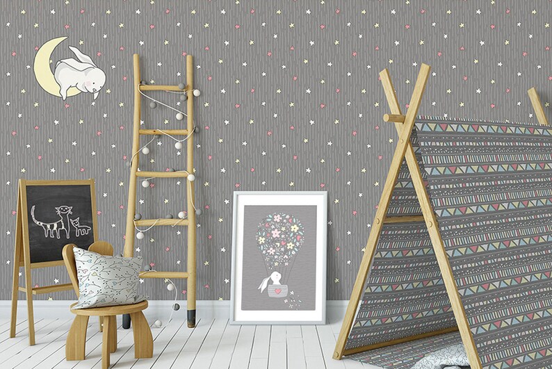 K&ouml;nnte beinhalten: Eine graue Kinderzimmertapete mit einem wei&szlig;en und rosa Sternenmuster. Die Tapete zeigt ein sich wiederholendes Muster aus Sternen und Herzen. Eine Holzleiter, ein Tipi-Zelt und ein gerahmtes Bild sind im Hintergrund.
