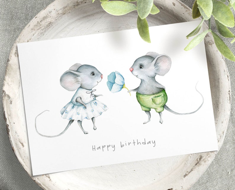 May include: A watercolor illustration of two mice, one in a blue dress and the other in green shorts, holding a blue flower. The text "Happy birthday" is written below the mice.