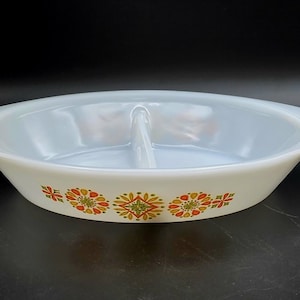 May include: White divided serving dish with a floral pattern in orange, yellow, and green. The dish has a handle on each side and a divider in the center. The dish is likely made of glass.