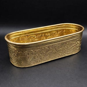 Könnte beinhalten: Eine weiße Keramik-Tasse mit schwarzem Henkel und dem Text "But First, Coffee" in fetter, schwarzer Schrift. Die Tasse steht vor einem neutralen Hintergrund, der ihr schlichtes Design hervorhebt.