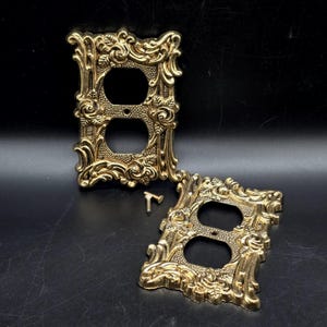 May include: A white ceramic mug with a black handle and the text "But First, Coffee" in a black, handwritten-style font. The mug is on a white surface.