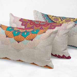 Può includere: Tre cuscini rettangolari con colorati disegni mandala. I cuscini hanno uno sfondo beige chiaro e presentano motivi intricati nelle tonalità dell'arancione, turchese, rosa e giallo. I cuscini sono disposti in modo leggermente sovrapposto.