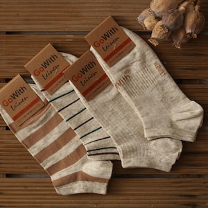 May include: Four pairs of beige socks with brown stripes. The socks are made of linen and have the text "GoWith Leinen" on the packaging.