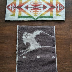 May include: Two rectangular fabric swatches. The top swatch is off-white with a geometric pattern in green, yellow, orange, and red. The bottom swatch is dark brown with a light-colored, stylized silhouette of a buffalo or bison in profile.