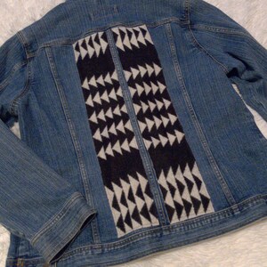 May include: A blue denim jacket with a black and white geometric pattern on the back.