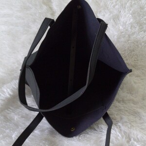 May include: A black tote bag with two handles. The bag is made of a soft, textured material and has a spacious interior.