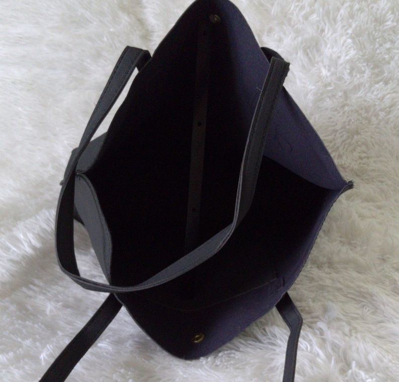 May include: A black tote bag with two handles. The bag is made of a soft, textured material and has a spacious interior.