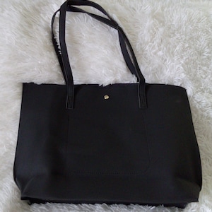 May include: A black tote bag with double straps and a small pocket on the front.