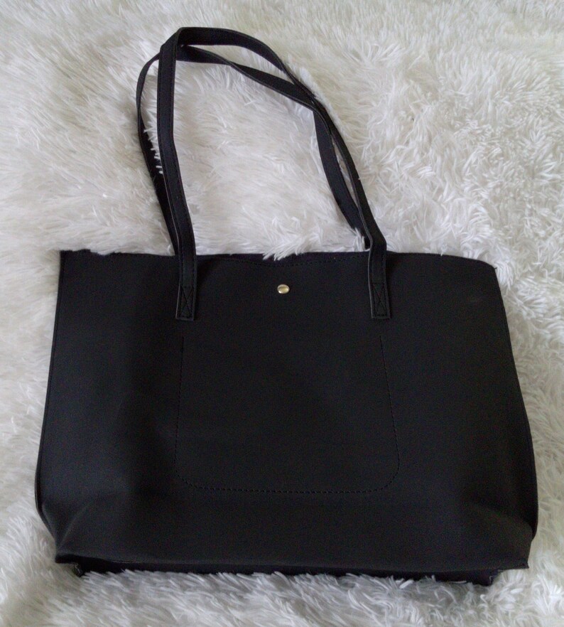 May include: A black tote bag with double straps and a small pocket on the front.