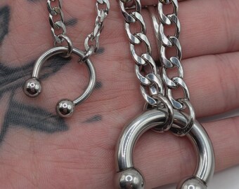 May include: Two silver-toned metal circular horseshoe-shaped pendants attached to silver-toned curb chains. Each pendant features a smooth, polished finish with a ball at each end of the open circle, suspended from a matching metallic link chain.