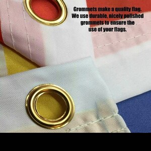 May include: Close-up of a white, red, and blue flag with gold grommets. The text "DURABLE GROMMETS" is written in blue letters. The text below reads "Grommets make a quality flag. We use durable, nicely polished grommets to ensure the use of your flags."