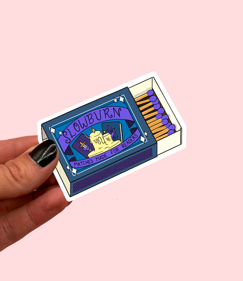 May include: A blue and purple matchbox sticker with the text "Slowburn" and "Matches Made For Readers". The matchbox has a drawing of a candle, a book, and a sword.