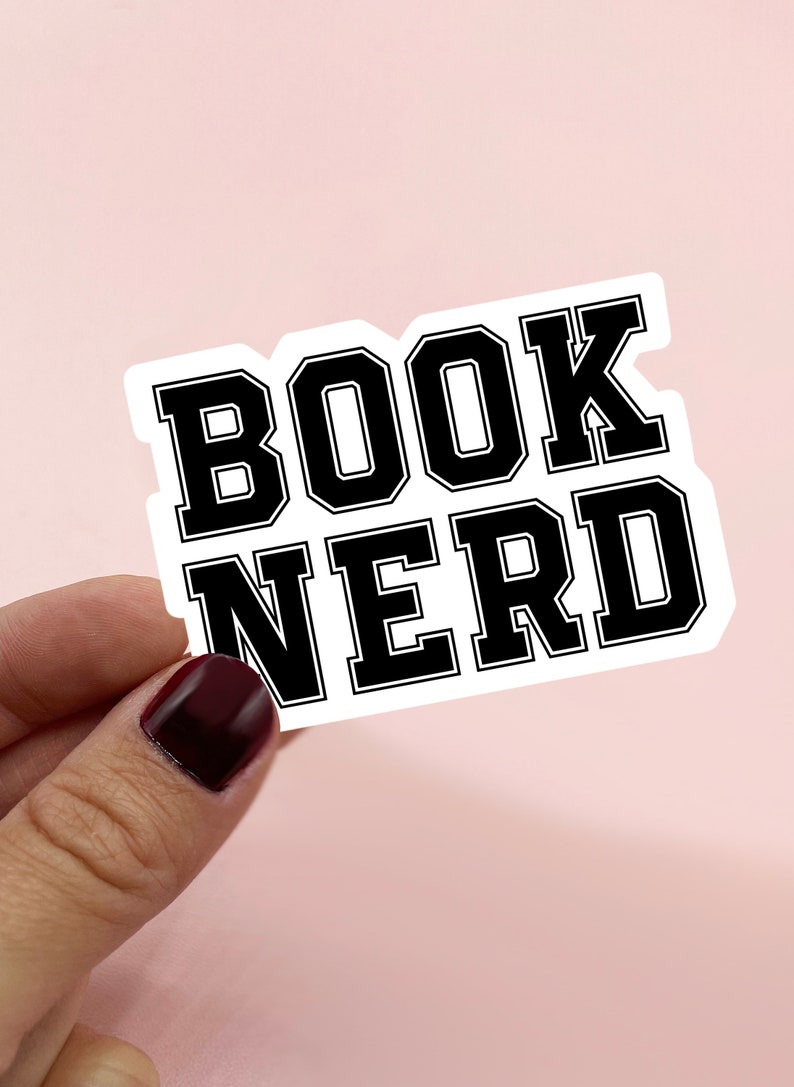 May include: A white sticker with black text that reads "BOOK NERD" in a varsity-style font.