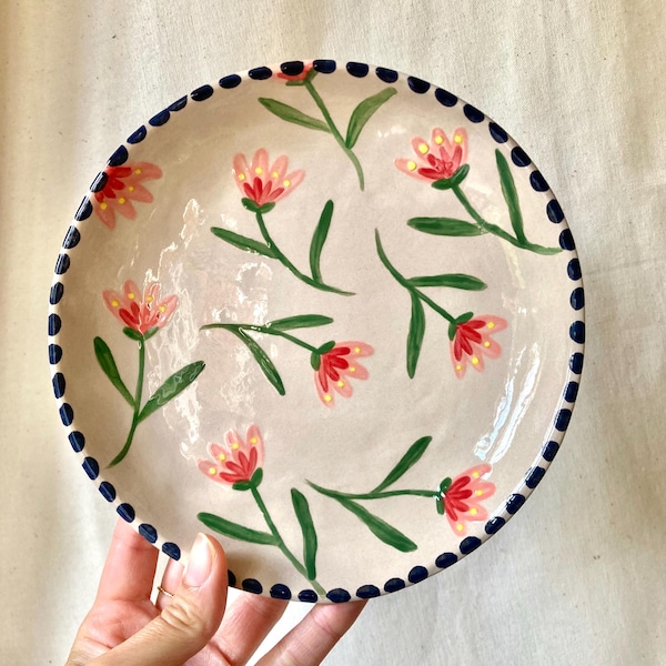 Plato de cerámica con flores rosas, rojas y amarillas, borde negro.