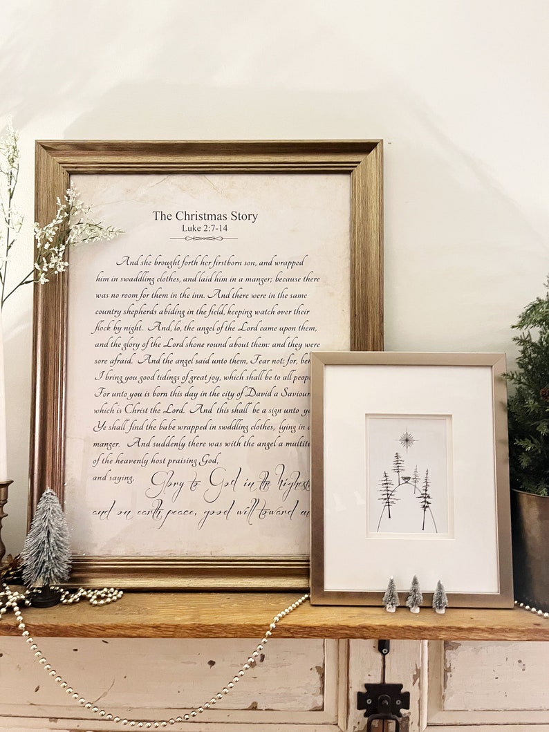 May include: A framed print with a white background and black text. The text is a passage from the Bible, Luke 2:7-14, telling the story of the birth of Jesus. The title of the print is "The Christmas Story". Below the text is a handwritten inscription that reads "Glory to God in the highest and on earth peace, good will toward men".