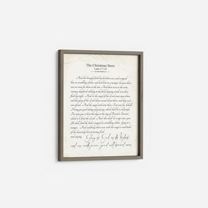 May include: A framed print with a beige background and black text. The text is a passage from the Bible, Luke 2:7-14, telling the story of the birth of Jesus. The title of the print is "The Christmas Story".
