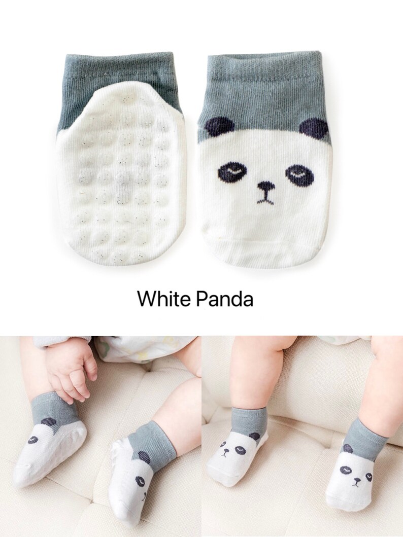 Puede incluir: Un par de calcetines blancos para beb&eacute; con un pu&ntilde;o gris y un dise&ntilde;o de cara de panda. Los calcetines tienen una parte inferior texturizada para agarre.