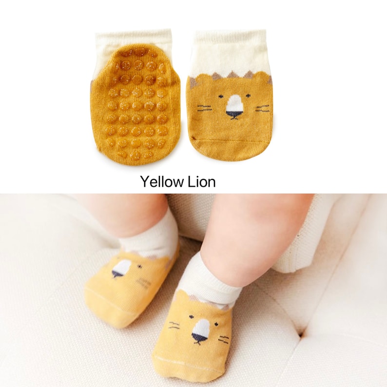 Puede incluir: Calcetines amarillos para beb&eacute; con un dise&ntilde;o de cara de le&oacute;n y puntos antideslizantes en la parte inferior. "Yellow Lion" est&aacute; escrito debajo de los calcetines.