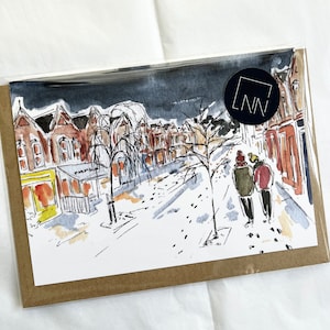 May include: Watercolour print depicting a snowy street scene with buildings and two figures. The artwork is in a clear plastic sleeve with a brown backing. A black circle with the letters "LNN" is on the upper right.
