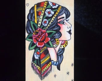 May include: A rectangular wooden plaque featuring a hand-painted illustration of a person in profile wearing a patterned headscarf with a large red rose and white flowers. The background is light wood with small black heart and star symbols.