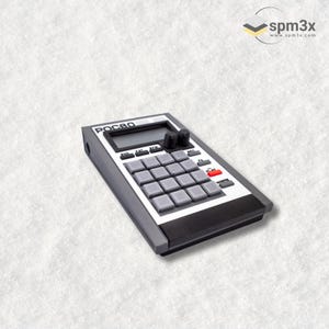 Peut inclure: Une boîte à rythmes noire et blanche avec une face avant grise et 16 pads. La boîte à rythmes possède un petit écran LCD et quelques boutons. Le texte "POC80" est imprimé sur la face avant.