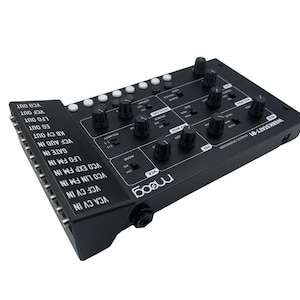 May include: A black Moog Werkstatt-01 analog synthesizer with a row of knobs and buttons on the top and a row of jacks on the side. The text "WERKSTATT-01" and "moog" are printed on the synthesizer.