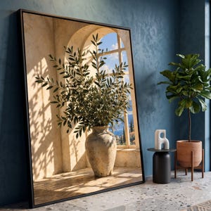 Könnte beinhalten: Ein großes, rechteckiges gerahmtes Wandbild mit dem Druck einer hohen, verwitterten Steinvase voller Olivenzweige, die vor einem Bogenfenster mit Blick auf eine Küstenlandschaft mit blauem Himmel und Meer steht.