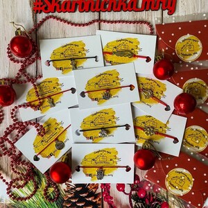 May include: A collection of red string bracelets with various charms, including a house, an owl, a star, and a key. The bracelets are displayed on white cards with a yellow background and the text "Скарбничка мрій" which translates to "Treasure Box of Dreams".