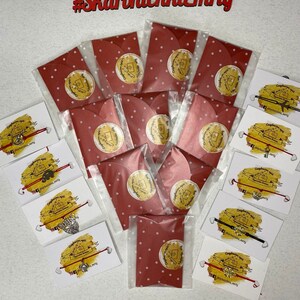 May include: A collection of red and white polka dot envelopes with a small white circle with a design in the center. The envelopes are arranged in a semi-circle around a collection of red and black string bracelets with silver charms. The bracelets are on white cards with the text "#Skartnlchka_mry" on them.