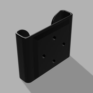 May include: Black plastic wall mount with four holes and a rounded edge. The mount is designed to hold a device.
