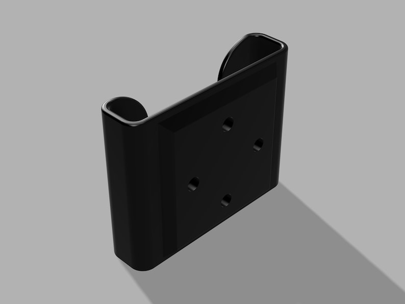 May include: Black plastic wall mount with four holes and a rounded edge. The mount is designed to hold a device.