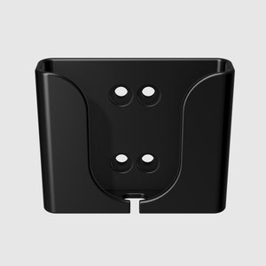 May include: Black plastic wall mount with two sets of holes for mounting screws. The mount has a curved shape to hold a device.