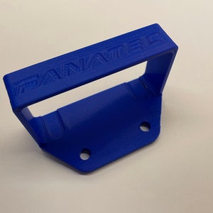 Puede incluir: Una manija de pl&aacute;stico azul con la palabra "FANATEC" en relieve en la parte superior. La manija tiene dos agujeros en la parte inferior.