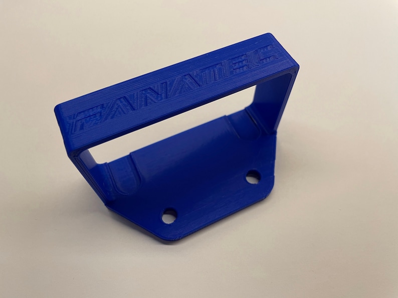 Puede incluir: Una manija de pl&aacute;stico azul con la palabra "FANATEC" en relieve en la parte superior. La manija tiene dos agujeros en la parte inferior.