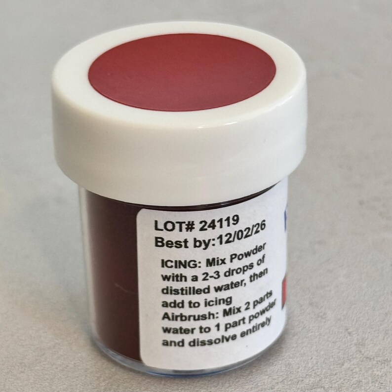 May include: A small, white jar with a red lid containing a brown powder. The label reads "LOT# 24119 Best by: 12/02/26 ICING: Mix Powder with a 2-3 drops of distilled water, then add to icing Airbrush: Mix 2 parts water to 1 part powder and dissolve entirely."