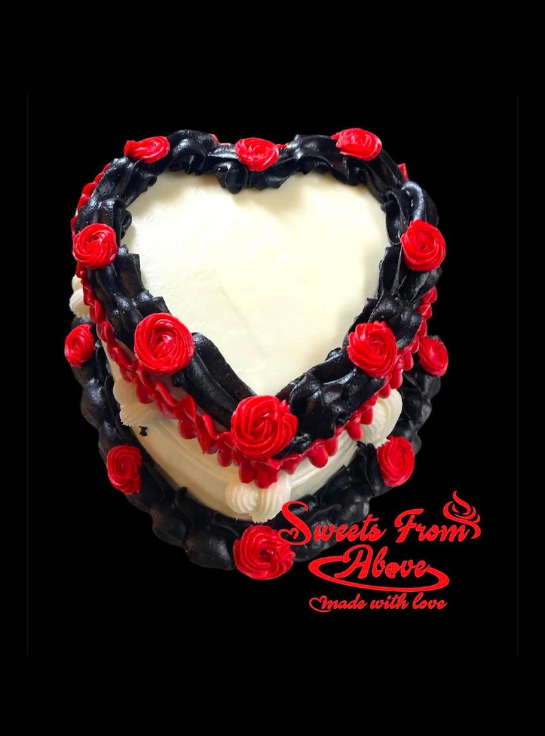 K&ouml;nnte beinhalten: Ein herzf&ouml;rmiger Kuchen, der mit schwarzem und rotem Frosting verziert ist. Der Kuchen ist mit roten Rosen verziert und die Worte "Sweets From Above" und "Made with love" stehen unten.
