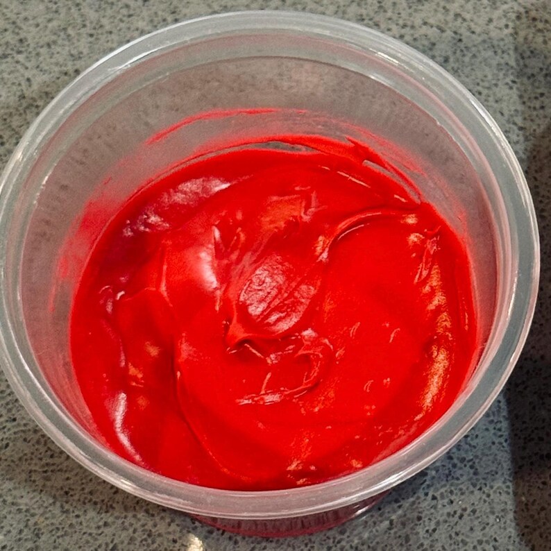 K&ouml;nnte beinhalten: Ein durchsichtiger Plastikbeh&auml;lter gef&uuml;llt mit leuchtend rotem Frosting oder Zuckerguss.