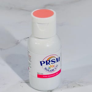 May include: A white bottle of pink baking gel with a coral-colored cap. The label features the text "PRISM SUGAR CO" with a rainbow logo and the words "PINK BAKING GEL". The bottle contains 1 oz of product.