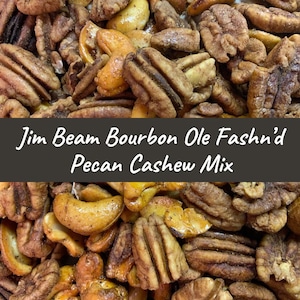 May include: Close-up of a mix of pecans and cashews, seasoned with spices and bourbon. The nuts are a light brown color and have a glossy finish. The text "Jim Beam Bourbon Ole Fashn'd Pecan Cashew Mix" is displayed on a black banner.