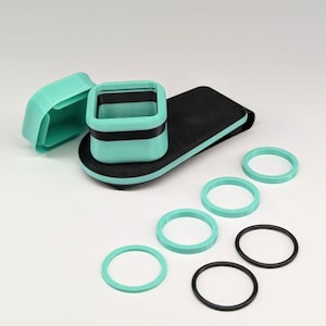 May include: A set of teal and black 3D printed camera lens adapters with a variety of teal and black rings.