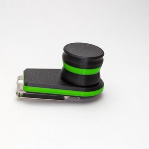 May include: A black and green clip-on phone holder with a swivel head. The holder has a green accent around the edge and a green stripe around the swivel head.