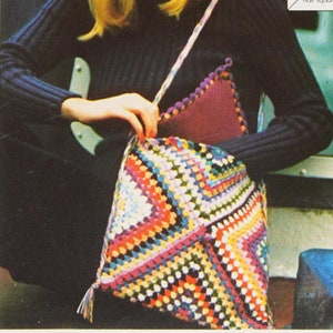 May include: A woman wearing a black turtleneck sweater and jeans is carrying a colorful crocheted tote bag with a purple lining. The bag is made with a granny square pattern and has a fringe tassel.